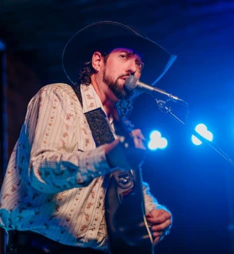 man playing guitar singing into microphone